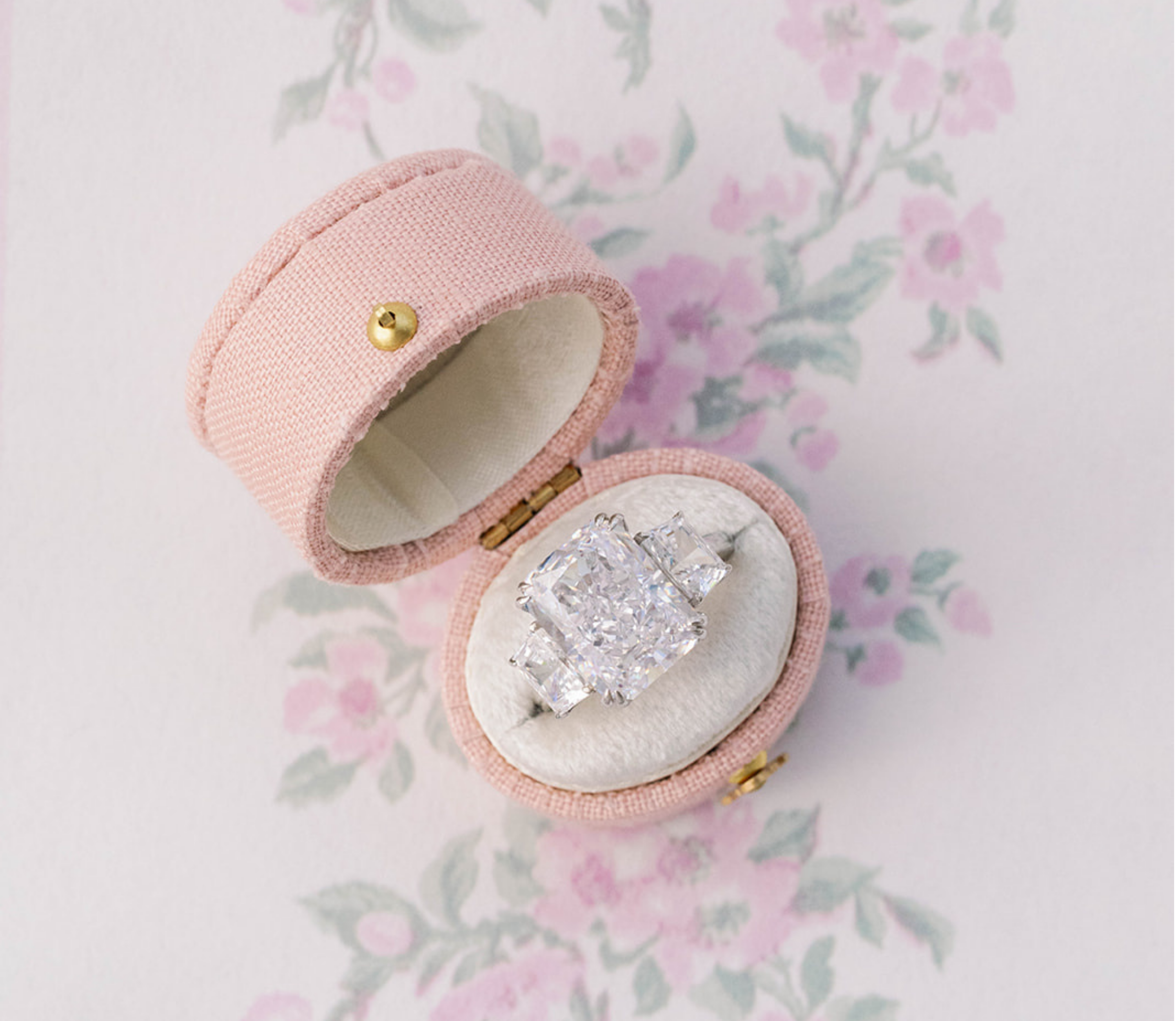 Diamond ring in a pink jewelry box on a floral background